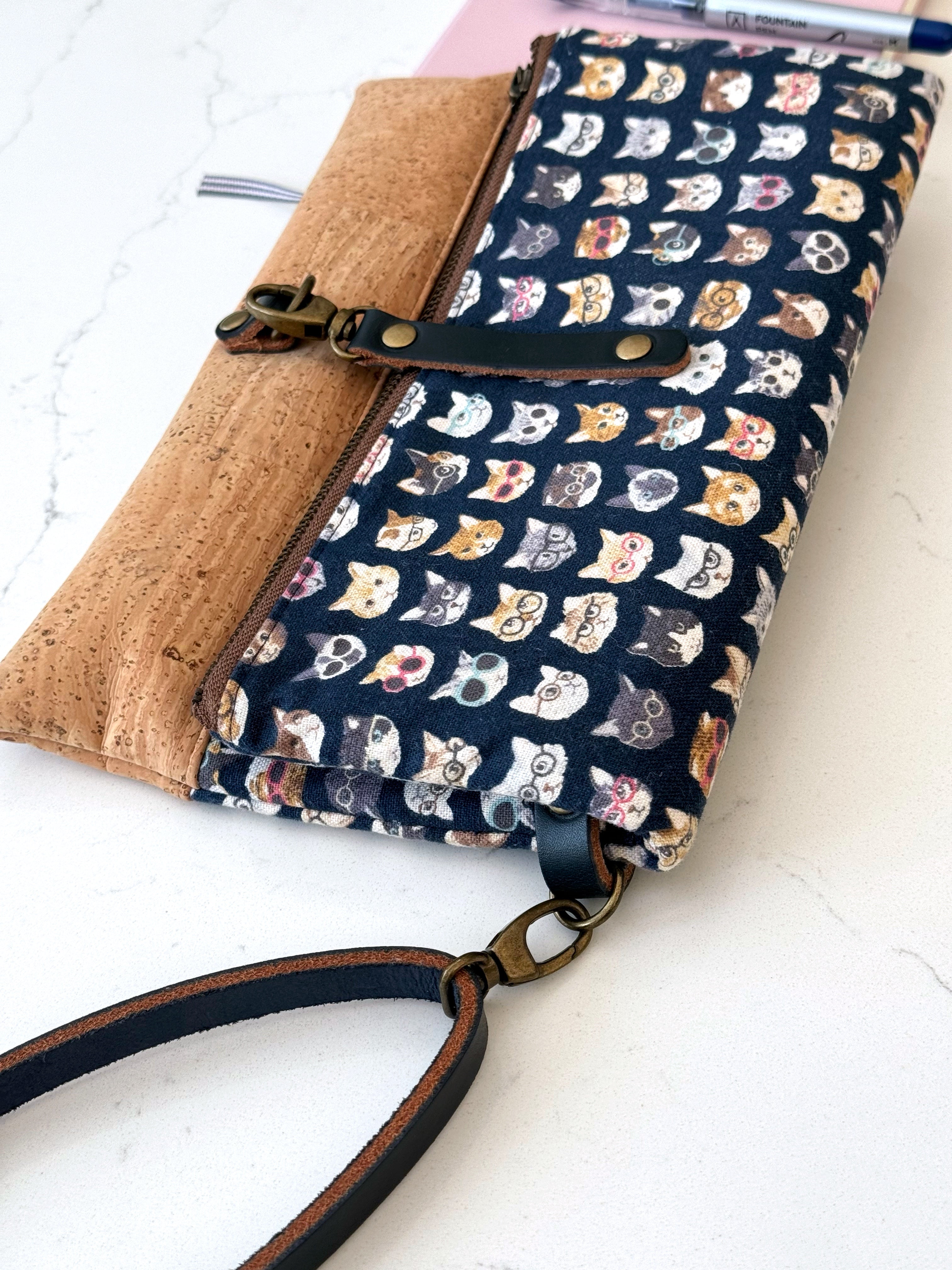 Cat clutch wallet with detachable wrist strap, brass swivel clasp top closure, and real navy leather.