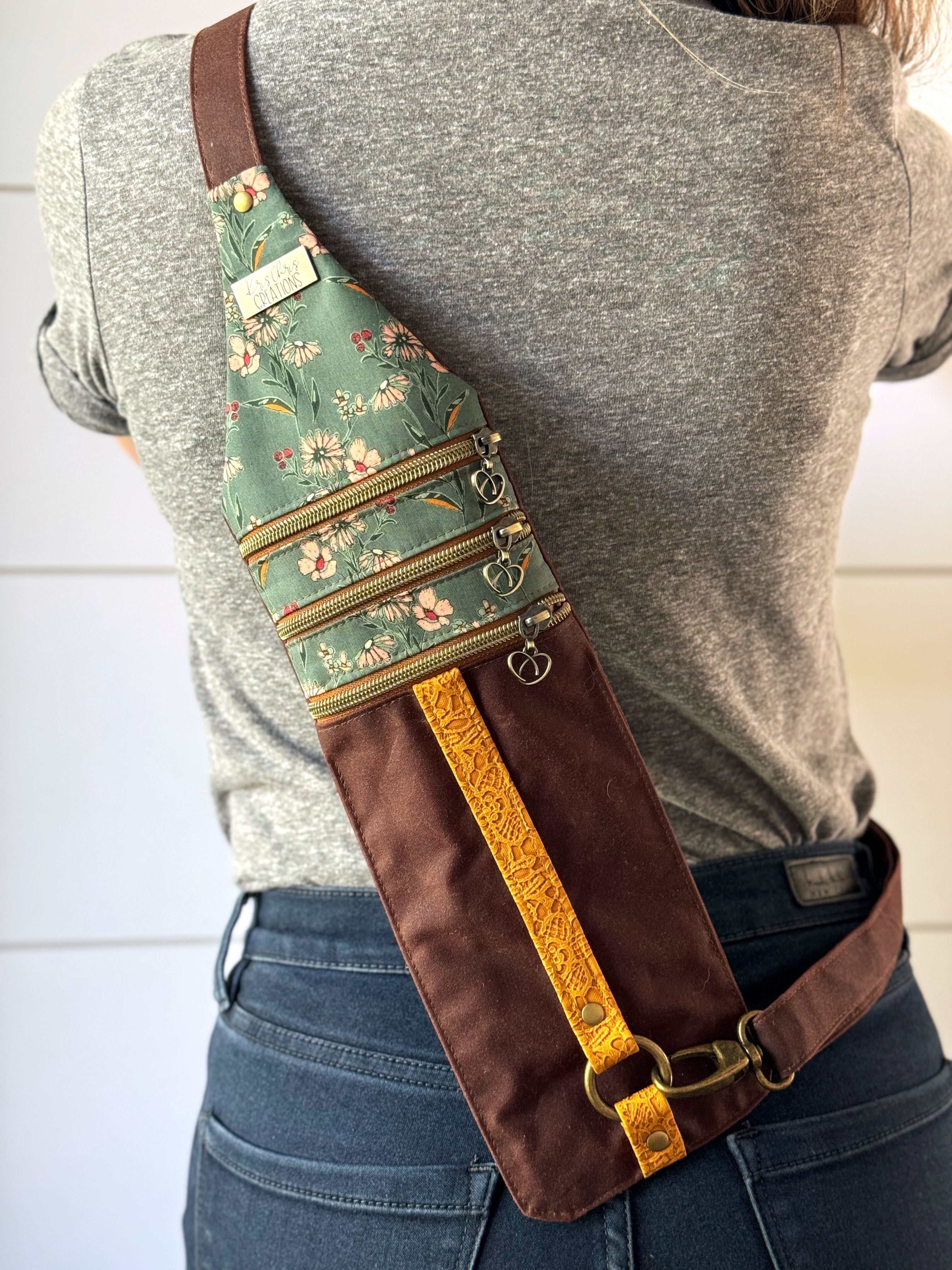 Reddish brown crossbody bag worn on the back with teal floral fabric on top and a yellow lace vinyl stripe