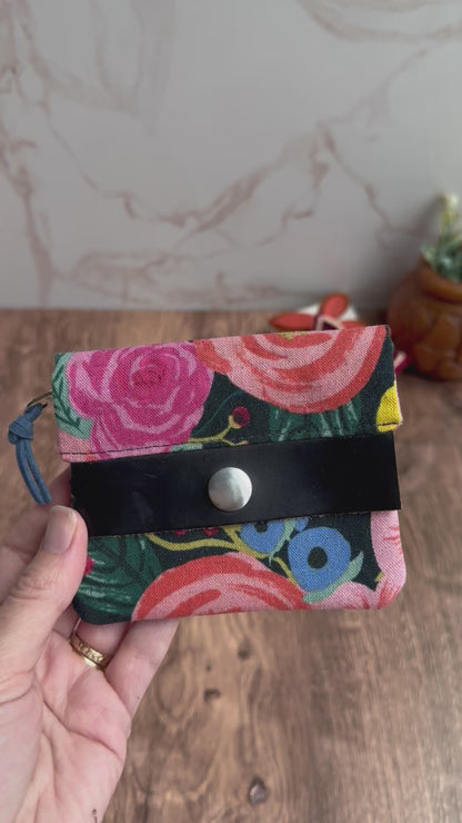 Mini Janet Wallet sewn from bright floral canvas fabrics from Rifle Paper. Black leather tab, silver snap, and zipper interior with cute little figures.