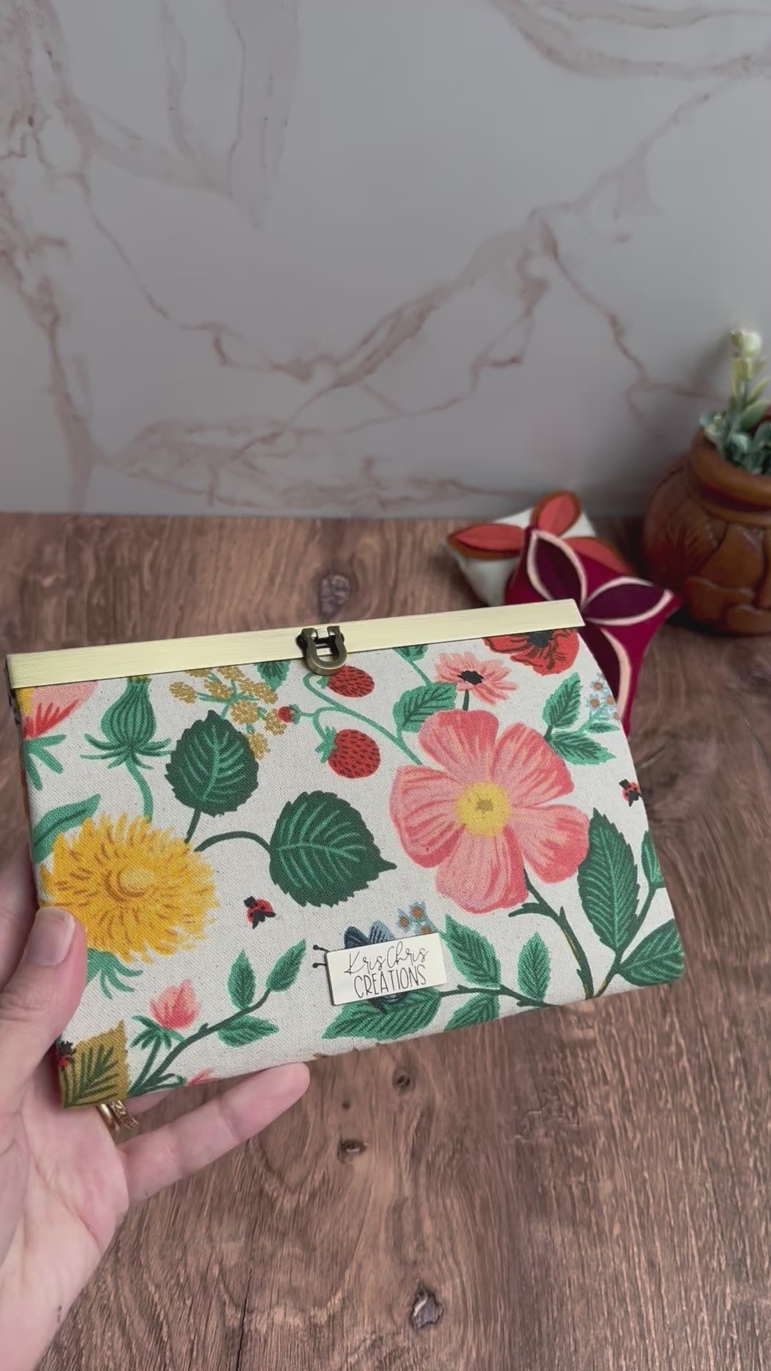 View of floral canvas accordion wallet and antique brass clasp. Interior have many card slots and colorful floral fabrics and interior zipper pocket