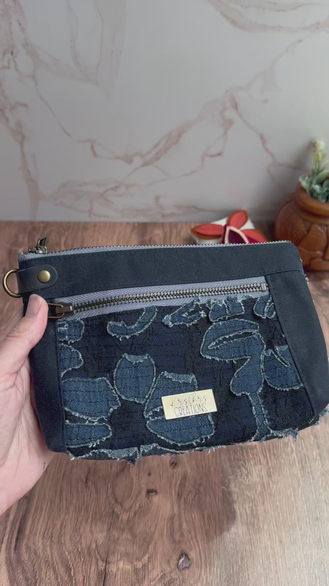 Floral denim waxed canvas navy pouch is shown with interior of zipper pockets showing cat lining and illustrated blue floral lining.